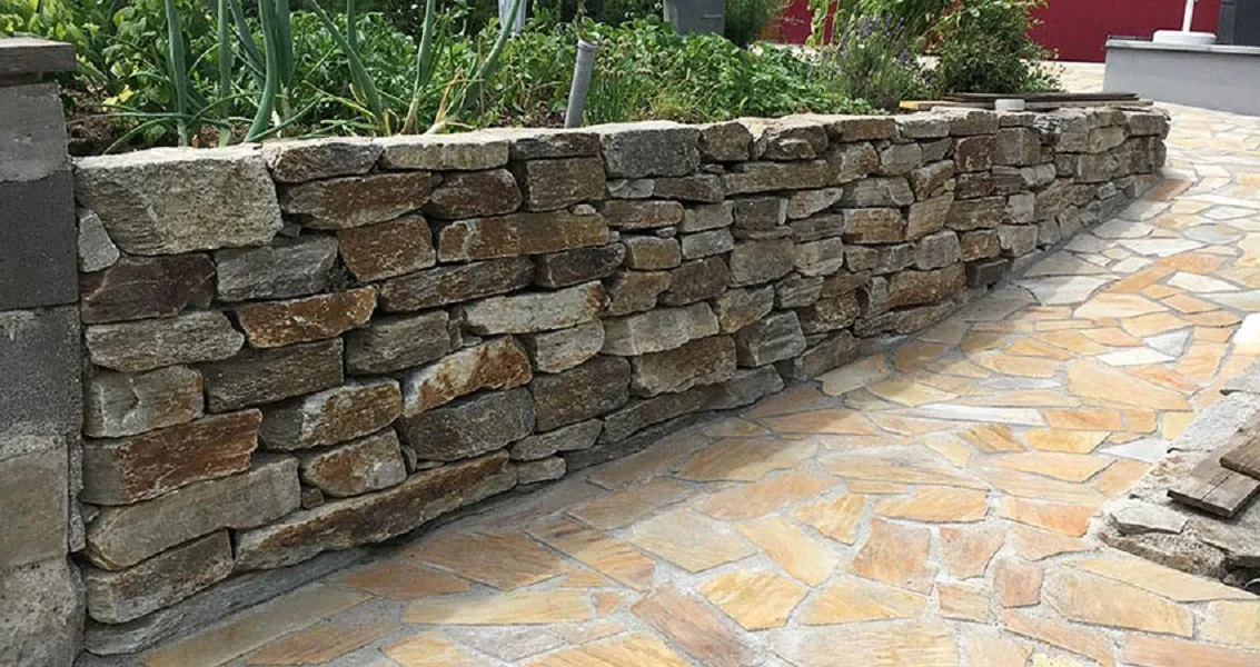 Natursteinmauer neben einem gepflasterten Weg